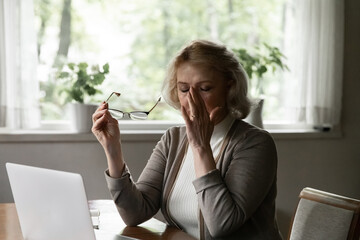 Exhausted stressed mature woman taking off glasses, touching massaging nose bridge, tired aged...