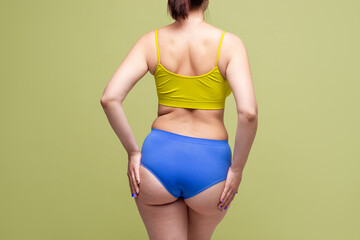 Woman in colorful underwear with toned buttocks on light green background