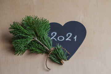 New Year's composition: a bouquet of fir branches and a heart with the inscription 2021 in chalk. Postcard New Year.