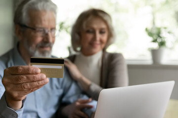 Close up mature couple shopping online together, elderly man holding plastic credit card, aged...