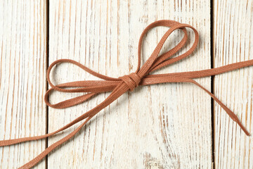 Brown shoelaces on white wooden background, top view