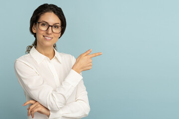 Smiling business woman wear white blouse and glasses pointing with finger, showing blank copy space...