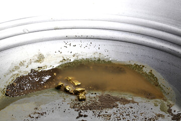 gold nuggets in a metal gold pan