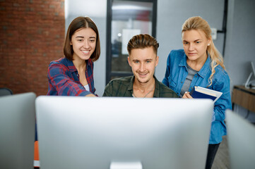 Smiling IT specialists works on computers, office