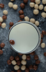 Bunch of cereal balls scattered around glass of fresh milk