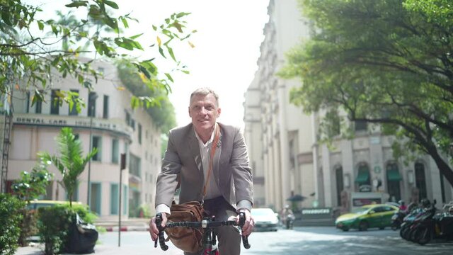 businessman ride a bicycle to working in the city downtown, business work lifestyle in urban, bike street way, concept to ecology park day in city, active work of businessperson in the morning, slow