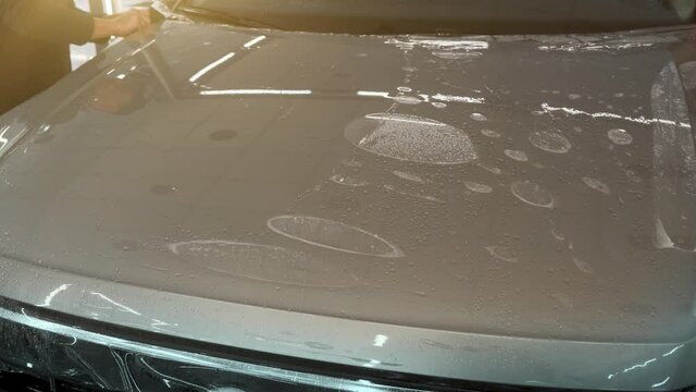 Process of installing of Paint Protection Film or PPF on new car in professional auto Detailing Center. Thin polyurethane film or polymer as protective skin from scratches and rock chips.