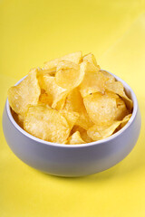 Potato chips in the gray ceramic bowl against the bright yellow background