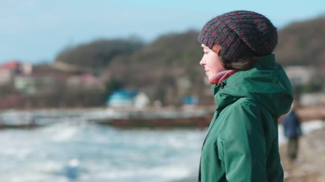 A young woman stands on the beach and inhales medicine in a nebulizer. Parallax. The concept of conservative treatment of asthma