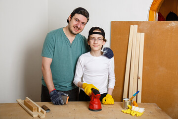 Father and son grind board or plywood with grinder. Teenager learns to work with grinder. Carpenter...