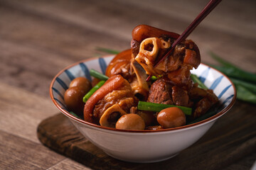 Eating Taiwanese food pork knuckle in a bowl with chopsticks