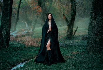Mysterious fantasy gothic woman dark witch obsessed by evil. Girl demon vampire in black dress cape...