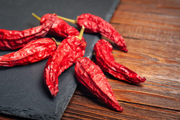 Red pepper on the table. A pile of dried red peppers stacked on a black slate stone. Hot chili peppers.