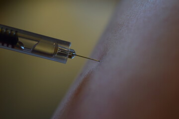 close up of an injection next to the skin of an arm