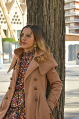 Portrait photo of a beautiful model leaning against a tree in the park.