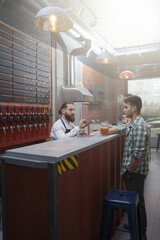 Vertical shot of a male customer at beer pub, talking to bartender