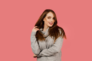 Professional model posing in studio. Lifestyle of caucasian happy girl. Beauty portrait of a woman weared grey sweater on pink background.