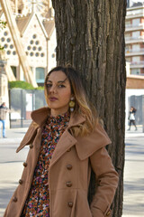 Portrait photo of a beautiful model leaning against a tree in the park.
