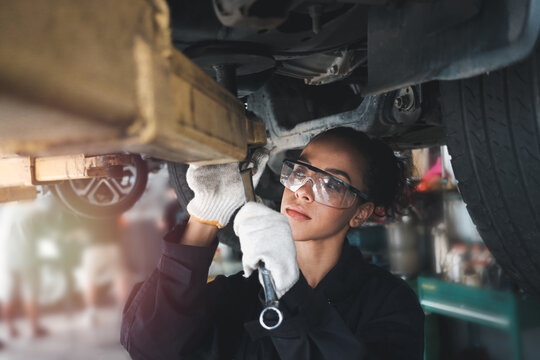 African Female auto mechanic work in garage, car service technician woman  in overalls check and repair customer car at automobile service center,  inspecting car under body and suspension system Stock-Foto