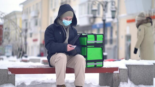 delivery man with green bagpack awaiting the order for delivery.