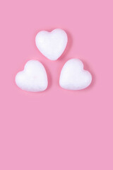 Three little white hearts on a pink background