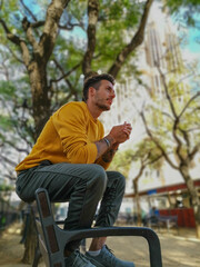 Obraz premium Man sitting on a bench in the park dressed in autumnal clothes.