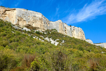 autumn view of landscape with limestone cliffs under blue sky and clouds