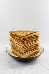 Russian Maslenitsa, Shrovetide, pancake week, carnival, shrove, pancake day. A stack of pancakes on plate, on light background, close-up. Soft focus.