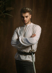 Portrait of handsome man in image of medieval king. Vintage clothing, historic white shirt retro...