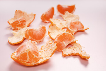 the peel of a tangerine lies on a white surface, and on top of it there are tangerine slices