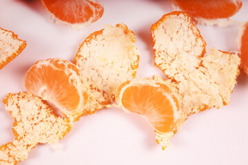 two slices of tangerine and the peel scattered side by side