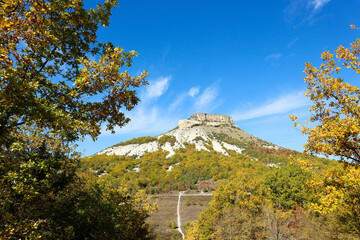 Tepe Kermen Cave City near Bakhchysarai in Crimea surrounded by colorful autumn forest under bright...