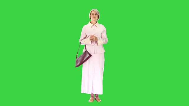 Old woman lady in pink dress standing and waiting on a Green Screen, Chroma Key.