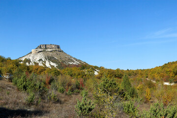Tepe Kermen Cave City near Bakhchysarai in Crimea surrounded by colorful autumn forest under bright...
