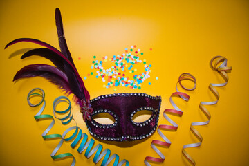 purple carnival mask with confetti on a yellow background
