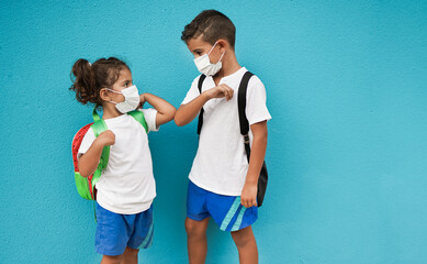 Children meet and greeting each other with elbows while wearing surgical face mask for coronavirus outbreak - School and safety measures for covid-19