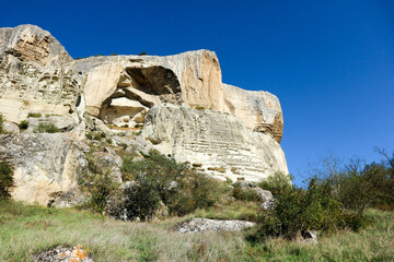 Fototapeta na wymiar scenic limestone cliff with caves with azure sky background in Crimea