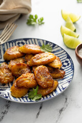 Fried caramelized plantains served with lime wedges and cilantro © fahrwasser