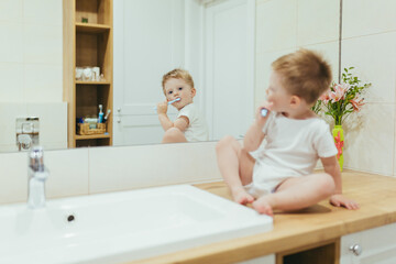 Little kid boy brushing teeth in his bathroom, baby taking care of teeth