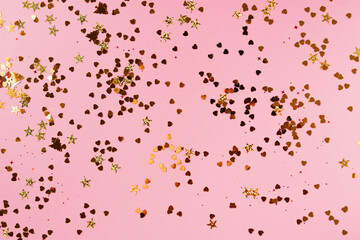 Golden confetti glitter on pink color pastel festive background.