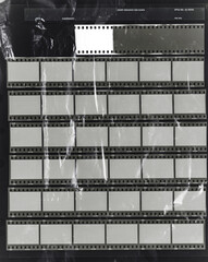 seven long 35mm black and white film strips on dark background behind foil material, empty photo frames. 