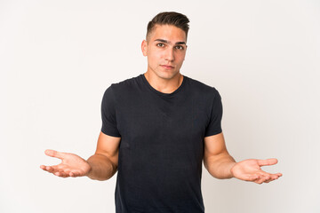 Young caucasian handsome man isolated doubting and shrugging shoulders in questioning gesture.