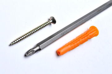 plastic dowel, screwdriver and several screws on a light background. close-up.