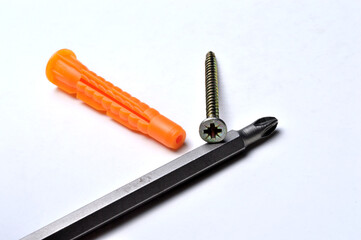 plastic dowel, screwdriver and several screws on a light background. close-up.