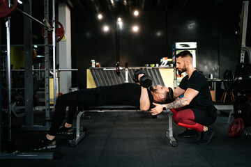 personal trainer helping and assisting man in the gym