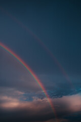 Fototapeta premium Double Rainbow across a cloudy sky in the rural Midwest. Prism of colors. Dramatic weather at sunrise. 