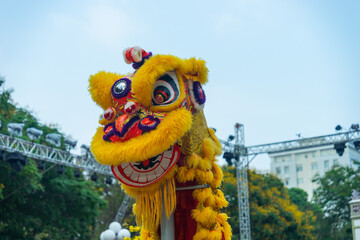 Lion dance - dragon & lion dance street performances. Yellow lion head with blue skies in background.