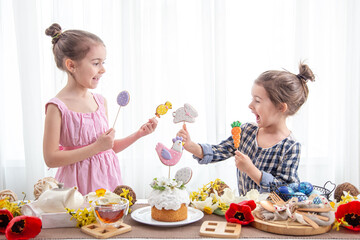 Two little girls decorate a festive cake for the Easter holiday.