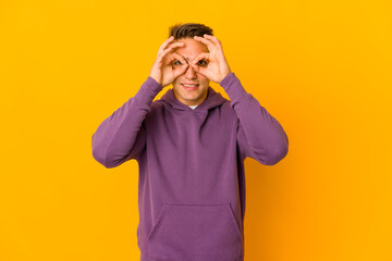 Young handsome caucasian man isolated showing okay sign over eyes