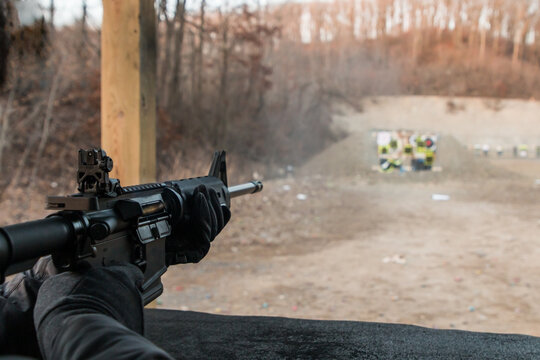 Person shooting a semi-automatic AR-15 assault weapon rifle at an outdoor gun range